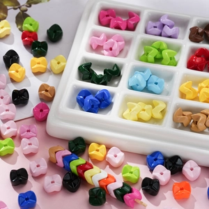 Colorful acrylic wavy cross beads for DIY jewelry and phone chains in a ceramic tray