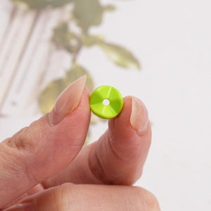 Close-up of grass green faceted acrylic round bead with center hole for DIY jewelry making