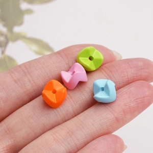 Macro detail of four colorful wavy acrylic beads held on a finger for DIY phone charms