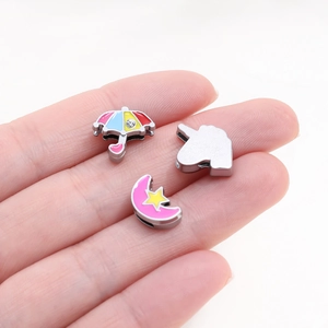 Detail of colorful enamel charms featuring umbrella, unicorn, and moon on a hand