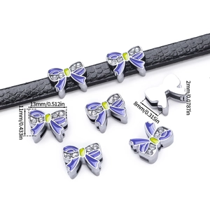 Detail view of purple enamel bow charm with rhinestones on a black leather strap