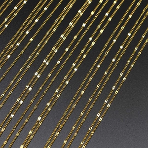 Polished golden stainless steel chain set with bead and curb styles on dark background