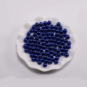 Macro-opname van diepblauwe ronde ABS-parels met gaten in een wit decoratief bord