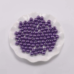 Macro-opname van paarse ABS-parels met gaatjes in een witte decoratieve sieradenschaal