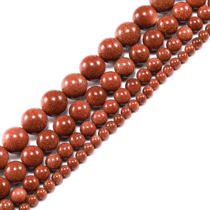 Detailed view of red goldstone beads in various sizes with a glittering metallic finish