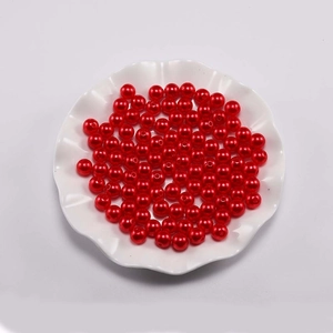 Macro detail van glanzende rode ronde ABS kralen voor sieraden in een witte keramische schaal