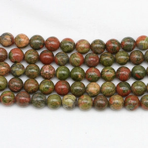 Detailed view of polished natural unakite stone round beads with green and pink texture