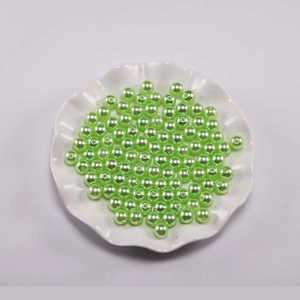 Macro-opname van lichtgroene ronde ABS-parels in een witte decoratieve schaal