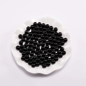 Macro-opname van glanzende zwarte ABS-parels in wit keramisch dienblad voor DIY-sieraden