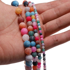 Colorful weathered crackle agate loose round beads held in palm showing various sizes