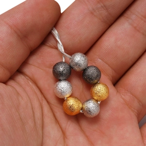Mano che tiene una collana a catena intrecciata con sette perline di metallo satinato misto