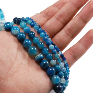 Primer plano de cuentas redondas de ágata azul con textura natural en la mano