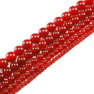 Multiple sizes of smooth red agate carnelian loose beads arranged in parallel rows