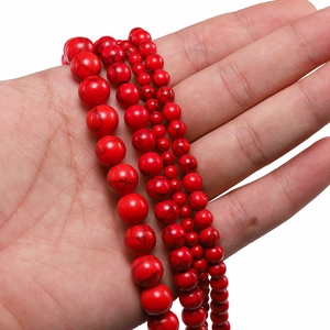 Detailed view of red turquoise beads with black veins in three different sizes on palm