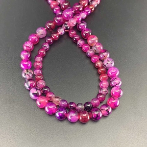 Pink dragon vein agate loose round beads for jewelry making on dark textured background