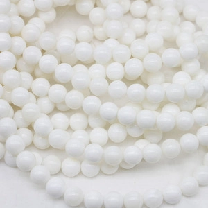Macro shot of polished white stone beads strand showing round shape and smooth texture