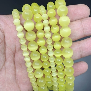 Handheld view of various sized 8mm white cat eye stone beads on elastic string