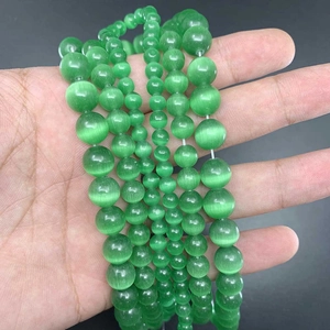 Detailed view of polished green cat eye round beads in various sizes for jewelry making