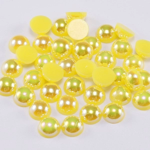 Detailed macro view of yellow half-round resin pearls with iridescent AB coating for DIY crafts