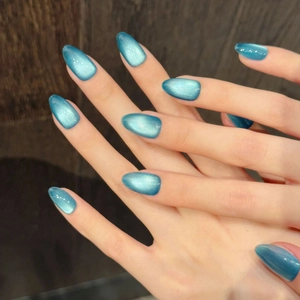 Glossy cat eye almond press-on nails in deep teal blue with shimmering magnetic finish