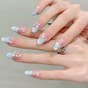 Blue cat-eye press-on nails with white bow designs and delicate pearl accents