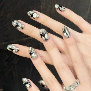Almond shaped silver crackle press-on nails with black starburst patterns and pearls