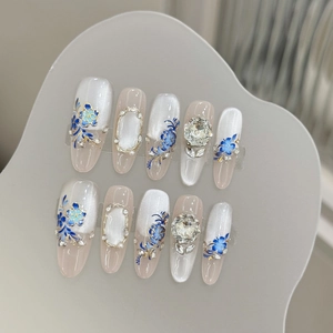 Blue floral press-on nails with cat-eye finish and gold accents in almond shape