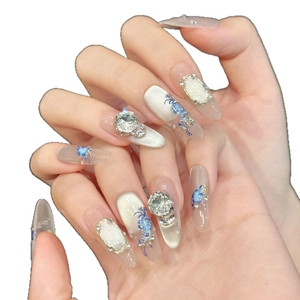 Blue porcelain style press-on nails with blue floral art, rhinestones, and cat-eye finish