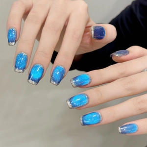 Blue cat eye press-on nails with silver French tips in a medium square shape