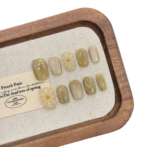 Sage green and gold 3D flower press-on nails with cat eye effect in a wooden tray