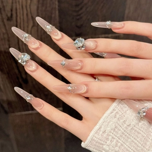 Luxurious long stiletto press-on nails with nude pink cat eye effect and rhinestone accents