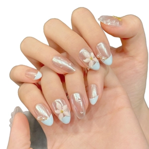 Short almond press-on nails with blue French tips, 3D floral accents, and aurora cat eye finish