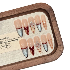 Handmade almond press-on nails with 3d flowers, cat eye effect and red accents on wood tray