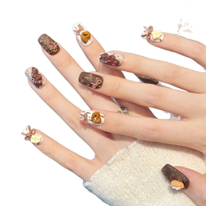 3D chocolate dessert style press-on nails with bow and cream relief on white background