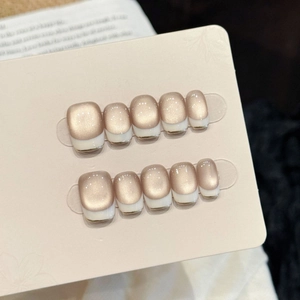 Cat eye press-on nails with nude pink base and white French tips on display card