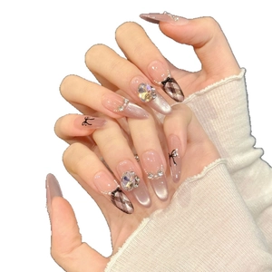 Pink almond press-on nails with silver cat-eye finish, bows, and sparkling rhinestones