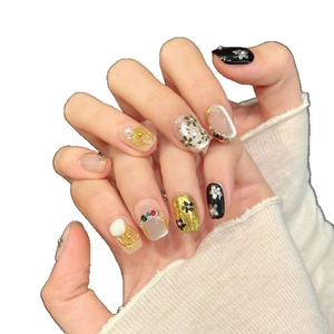 Faux ongles baroques avec fleurs en perles et détails métalliques sur les mains