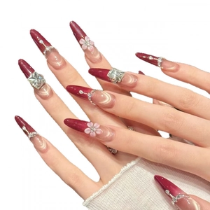 Burgundy cat eye press-on nails with 3D floral accents and rhinestones on white background