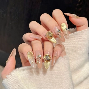 Nude and gold cat-eye gradient press-on nails with champagne rhinestones for luxury look