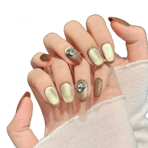 Champagne cat eye and amber faux nails in oval shape with sparkling rhinestone accents