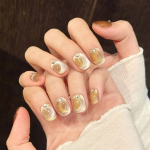 Faux ongles œil-de-chat marron doré avec strass argentés sur ongles carrés courts