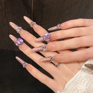 Pink purple stiletto press-on nails with heart gemstones and pearls on dark background
