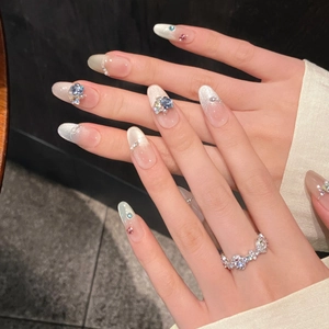 Rainbow cat-eye press-on nails with 3D crystals and pearl bow accents on long oval shapes