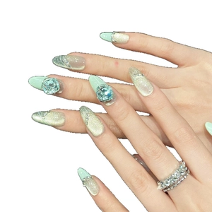 Mint green cat eye press-on nails in long almond shape with blue rhinestones