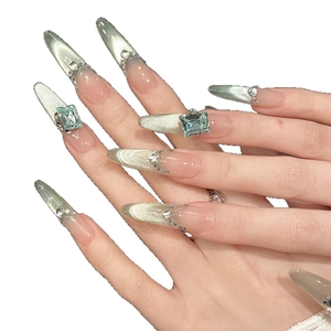 Long stiletto cat-eye press-on nails in mint green with rhinestones and gems