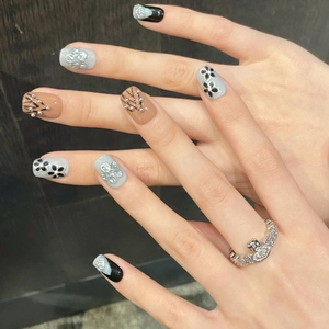 Handmade press-on nails featuring black floral patterns and 3D silver relief accents