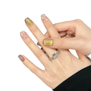 Hand wearing saturn-shaped ring with heart stone and cat-eye chameleon fake nails
