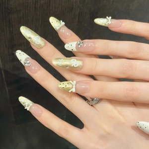 French style almond press-on nails with 3D bows, gold glitter, and pearl white accents