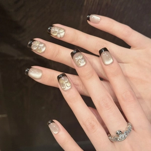 Short square press-on nails with black French tips, cat eye finish and 3D flower accents