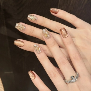 Cat eye press-on nails in amber brown with gold foil flakes and shimmer finish